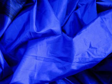 Katlanmış mavi kumaş yumuşak, dalgalı çizgiler oluşturur, mavi kumaş pürüzsüz kıvrımlar ve akışkan hareketler sergiler. Yumuşak kıvrımlı koyu mavi kumaş zarif bir doku için mükemmel bir akış yaratır..