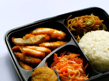 Katsu tavuğu, pilav, şehriye, patates püresi, sebze salatası ve börek, izole edilmiş beyaz bento kutusunda servis edilir, kopyalama alanı. Öğrenciler için uygun ve yoğun bir öğle yemeği. Besleyici gıdaları dengelemek. 