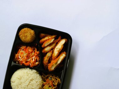 Katsu tavuğu, pilav, şehriye, patates püresi, sebze salatası ve börek, izole edilmiş beyaz bento kutusunda servis edilir, kopyalama alanı. Öğrenciler için uygun ve yoğun bir öğle yemeği. Besleyici gıdaları dengelemek. 