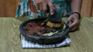 Endonezyalı bir kadının elleri sambal için taş bir havanda baharat öğütüyor. Geleneksel Endonezya sambali havan ve tokmakla hazırlanıyor. Asyalı kadınların elleri biber ve baharatları öğütücüde eziyor..