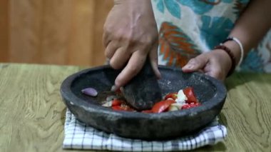 Endonezyalı bir kadının elleri sambal için taş bir havanda baharat öğütüyor. Geleneksel Endonezya sambali havan ve tokmakla hazırlanıyor. Asyalı kadınların elleri biber ve baharatları öğütücüde eziyor..