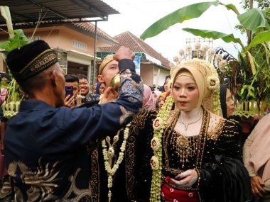 Sungkeman is sacred processions in traditional Javanese weddings. The bride and groom kneel before their parents to ask for blessings and prayers. Couple wearing traditional Javanese clothes during wedding ceremony clipart