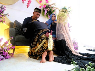 Sungkeman geleneksel Cava düğünlerinde kutsaldır. Gelin ve damat dua etmek için ailelerinin önünde diz çöker. Düğün töreninde geleneksel Cava kıyafetleri giyen çift.