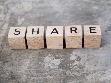 Paylaşım sözcüğünün üst görüntüsü ahşap küp bloğu ve desenli gri arka plan. Motivasyon kavramı