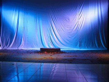 Mavi ışıklı arka ekranlı performans sahnesi. Merkezinde yuvarlak bir sahne var. Sanat performansı sahne konsepti