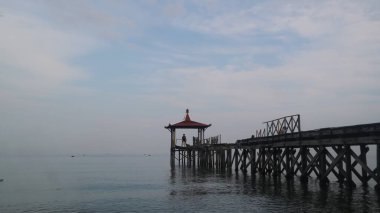 Pantai Pasir Putih Situbondo Endonezya 'da ahşap iskelede güzel bir gün doğumu manzarası, turizm gezisi merkezi.
