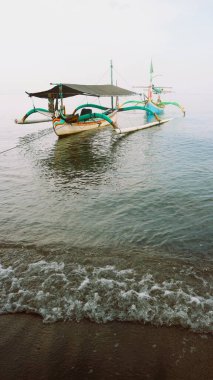 Sahil kıyısında açık gri gökyüzü arka planıyla renkli bir balıkçı teknesi.