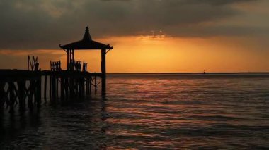 Endonezya, Pantai Pasir Putih Situbondo 'daki ahşap iskeleli güzel gün batımı manzarası. Doğa fotoğrafı kompozisyonu. Uzun Pozlandırma. 