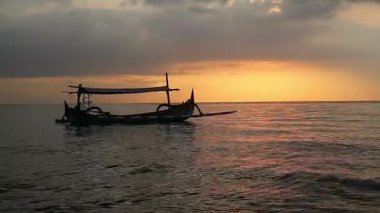 Tropik sahilde günbatımında balıkçı teknesi Pasir Putih, Endonezya Situbondo sahilinde.