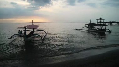 Tropik sahilde günbatımında balıkçı teknesi Pasir Putih, Endonezya Situbondo sahilinde.