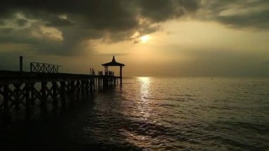 Endonezya, Pantai Pasir Putih Situbondo 'daki ahşap iskeleli güzel gün batımı manzarası. Doğa fotoğrafı kompozisyonu. Uzun Pozlandırma.