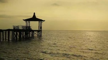 Endonezya, Pantai Pasir Putih Situbondo 'daki ahşap iskeleli güzel gün batımı manzarası. Doğa fotoğrafı kompozisyonu. Uzun Pozlandırma.
