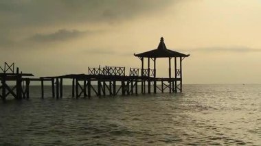 Endonezya, Pantai Pasir Putih Situbondo 'daki ahşap iskeleli güzel gün batımı manzarası. Doğa fotoğrafı kompozisyonu. Uzun Pozlandırma.