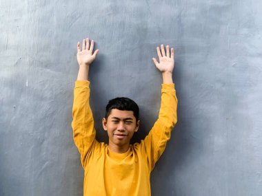 Sarı tişörtlü Güneydoğu Asyalı bir gencin özgün portresi. Neşeli ve umut dolu ifadesi egzotik ve enerjik bir enerji yakalıyor.