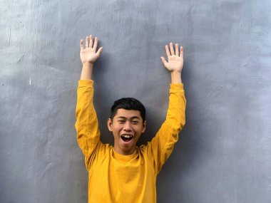 Sarı tişörtlü Güneydoğu Asyalı bir gencin özgün portresi. Neşeli ve umut dolu ifadesi egzotik ve enerjik bir enerji yakalıyor.