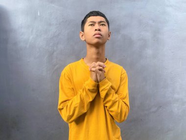 Sarı tişörtlü genç bir adam samimi bir duayla ve sessiz bir yansımayla yakalanır. Hristiyan ve ilham verici bir İncil dizesi geçmişi için mükemmeldir.