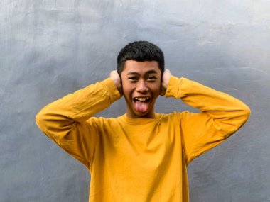 Neşeli bir Güneydoğu Asyalı adam, komik bir ifadeyle, kahkaha ve mutluluğun ruh sağlığı için güçlü bir ilaç, komik bir yüz olduğu fikrini somutlaştırıyor.