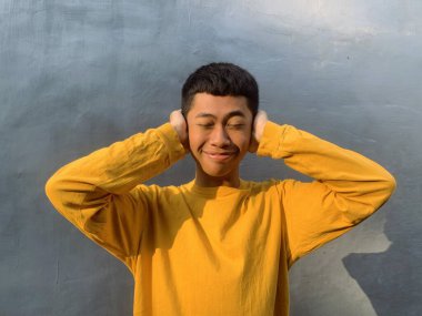 Neşeli bir Güneydoğu Asyalı adam, komik bir ifadeyle, kahkaha ve mutluluğun ruh sağlığı için güçlü bir ilaç, komik bir yüz olduğu fikrini somutlaştırıyor.