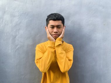 Sarı tişörtlü Güneydoğu Asyalı bir gencin özgün portresi. Neşeli ve umut dolu ifadesi egzotik ve enerjik bir enerji yakalıyor.