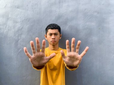 Sarı tişörtlü Asyalı bir adam, dur ya da geri çevir, gri arka plan, kopyalama alanı...