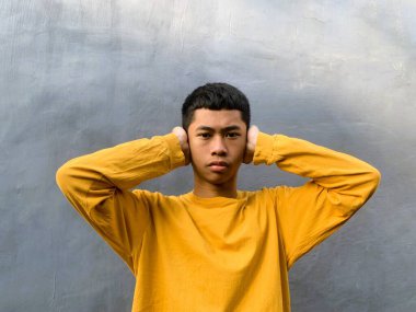 Sarı tişörtlü Güneydoğu Asyalı bir gencin özgün portresi. Neşeli ve umut dolu ifadesi egzotik ve enerjik bir enerji yakalıyor.