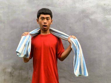 A southeast asian teenager with an expressive face poses with towel
