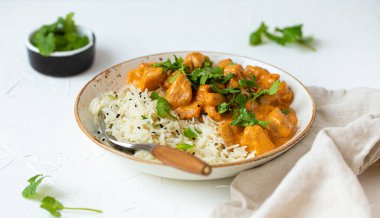 Geleneksel Hint yemeği körili tavuk Basmati pilavı ve taze kişniş beyaz tabak üzerine beyaz beton mutfak masası, seçici bir odak ile kapatın. Hint yemeği.