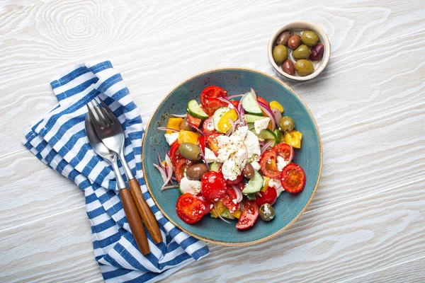 Beyaz ahşap arka plan manzaralı mavi seramik kasede beyaz zeytinli Yunan sağlıklı salatası, Akdeniz diyeti, Yunanistan 'ın geleneksel mutfağı