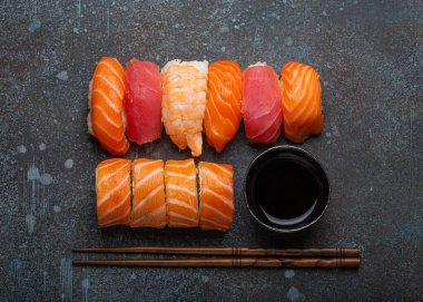 Set of traditional Japanese sushi and rolls top view with soy sauce and chopsticks on rustic stone background. Sushi with salmon, tuna and shrimp