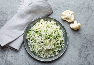 Çiğ karnabahar pirinci ya da dereotlu kuskus, keto diyeti için sağlıklı düşük karbonhidrat sebze tabağı ve gri beton arka planda sağlıklı düşük kalori besin