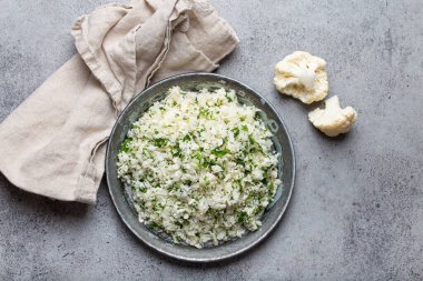 Çiğ karnabahar pirinci ya da dereotlu kuskus, keto diyeti için sağlıklı düşük karbonhidrat sebze tabağı ve gri beton arka planda sağlıklı düşük kalori besin