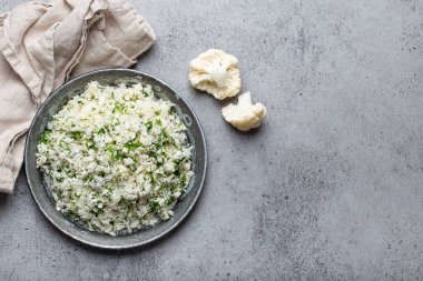 Çiğ karnabahar pirinci ya da dereotlu kuskus, keto diyeti için sağlıklı düşük karbonhidrat sebze tabağı ve gri beton arka planda sağlıklı düşük kalori besin, kopyalama alanı