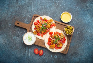 Geleneksel Yunan yemekleri pişirme: Sebzeli, etli, otlu, sade ahşap kesim tahtasında zeytin ekmeği, koyu mavi taştan arka planda zeytinyağı manzarası.