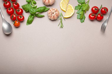 Taze kiraz domatesleri, otlar, sarımsak karanfilleri, limon dilimleri, mutfak kaşığı ve çatallı kompozisyon.