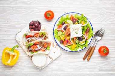 Geleneksel Yunan Yemeği: Yunan Salatası, et ve sebzeli jiroskoplar, Tzatziki sosu, beyaz rustik ahşap masa üstü manzaralı zeytinler. Yunanistan Mutfağı