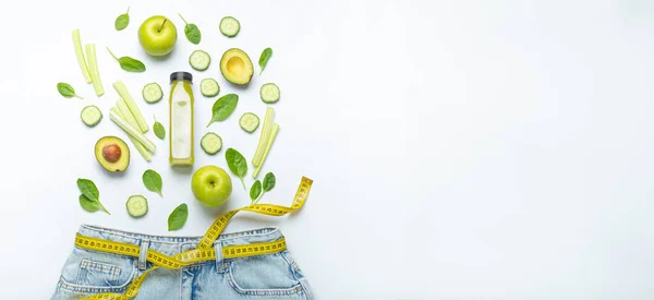 Grünes Obst Gemüse Smoothie Jeans Und Gelbes Maßband Statt Gürtel lizenzfreie Stockbilder