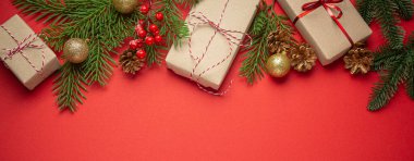 Noel ya da Yeni Yıl kutlamaları kırmızı kağıt şenliği arka planında süsleme köknar ağacı, hediye kutuları, koniler, böğürtlenler, parlak kırmızı toplar. Metin için boşluk..