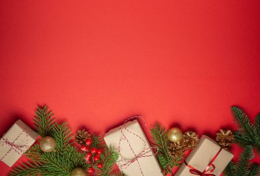 Noel ya da Yeni Yıl kutlamaları kırmızı kağıt şenliği arka planında süsleme köknar ağacı, hediye kutuları, koniler, böğürtlenler, parlak kırmızı toplar. Metin için boşluk..