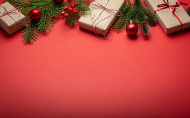 Noel ya da Yeni Yıl kutlamaları kırmızı kağıt şenliği arka planında süsleme köknar ağacı, hediye kutuları, koniler, böğürtlenler, parlak kırmızı toplar. Metin için boşluk..