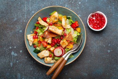 Geleneksel Levant yemeği Fattoush salatası, Arap mutfağı, pide ekmeği, kızarmış ekmek, sebze ve bitkilerden yapılır. Sağlıklı Orta Doğu vejetaryen salatası tabakta, koyu mavi arka plan manzarası.