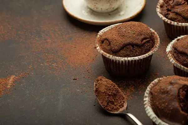 Chocolate and cocoa browny muffins with coffee cappuccino in cup angle view on brown rustic stone background, sweet homemade dark chocolate cupcakes, space for text.