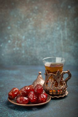 Ramazan ayında kurutulmuş tarihlerle oruç tutmak, tarihli iftar yemeği ve geleneksel bardakta Arap çayı, kırsal mavi arka planda açı manzarası. Müslüman ziyafeti.