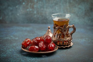 Ramazan ayında kurutulmuş tarihlerle oruç tutmak, tarihli iftar yemeği ve geleneksel bardakta Arap çayı, kırsal mavi arka planda açı manzarası. Müslüman ziyafeti.