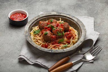 Köfteli ve domates soslu leziz spagetti. Köy masasında, düzgün düzenlenmiş çatal bıçak, peçete ve İtalyan mutfağı.