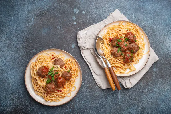 İki tabak sulu köfte ve domates sosuyla kaplı spagetti makarna klasik ve rahatlatıcı bir İtalyan yemeği yaratır.