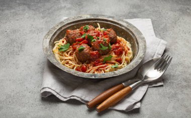 Köfteli ve domates soslu leziz spagetti. Köy masasında, düzgün düzenlenmiş çatal bıçak, peçete ve İtalyan mutfağı.