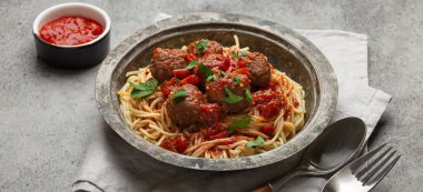 Köfteli ve domates soslu leziz spagetti. Köy masasında, düzgün düzenlenmiş çatal bıçak, peçete ve İtalyan mutfağı.