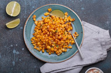 Meşhur bir Meksika sokak yemeği olan esquites tabağı limon dilimleri ve acı biberli ekşi kremayla servis edilir.