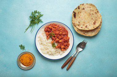 Mavi arka planda basmati pilavı, chapati ve çatal bıçak ile nefis köri soslu tavuk. Üst manzara ev yapımı Hint yemeklerini gösteriyor. Öğlen veya akşam yemeği için baharatlı ve lezzetli.