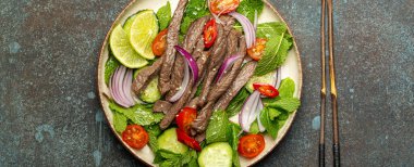 Geleneksel Tayland bifteği salatası, sebzeli ve naneli. Beton kaplama arka planda servis ediliyor. Sağlıklı egzotik Asya yemeği..